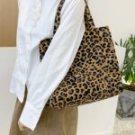 Affirmez votre style avec le sac à main fourre-tout Léa, paré d'un saisissant imprimé léopard, capturé dans une mise en situation élégante, porté avec allure sur l'épaule.