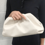 Femme tenant un sac à main en similicuir blanc.