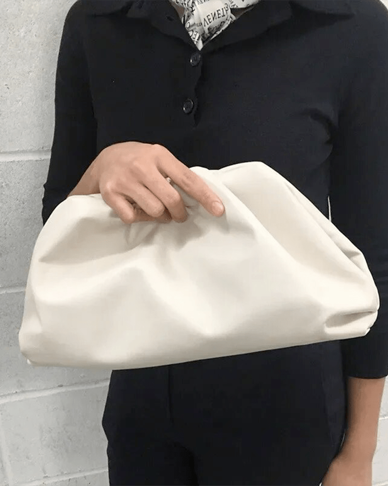 Femme tenant un sac à main en similicuir blanc.