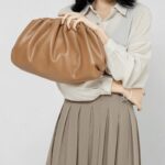 Femme tenant un sac à main en similicuir caramel.