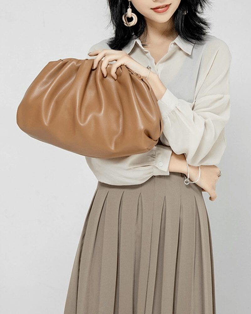 Femme tenant un sac à main en similicuir caramel.