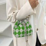 Image d'un sac à main pour femmes, motif damier vert porté au bras.