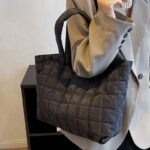 Femme portant sur l'épaule un sac à main fourre-tout matelassé noir Rebeca - Boutique Izamel.