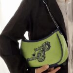 Manel : Sac à main d'épaule tenu à la main par une femme - Symbole d'élégance.