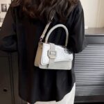 Femme chic portant le sac à main Gloria argenté, une déclaration de style étincelante.