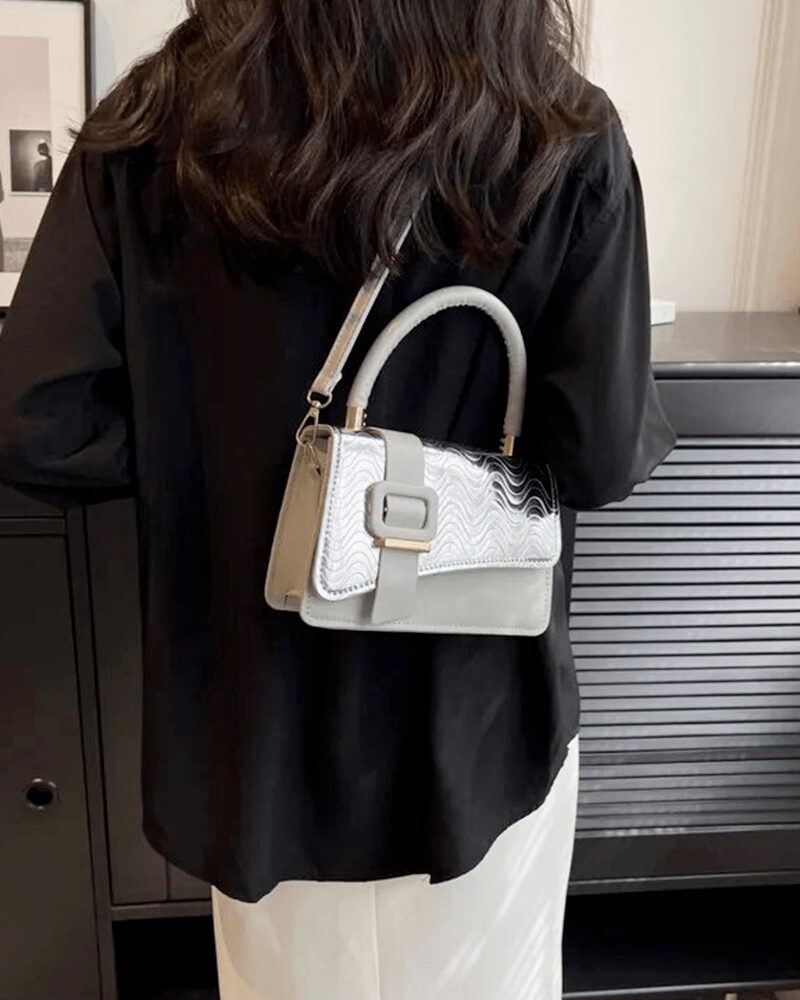 Femme chic portant le sac à main Gloria argenté, une déclaration de style étincelante.