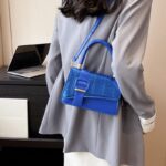 Femme sophistiquée portant le sac à main Gloria bleu, un accessoire chic pour une allure affirmée.