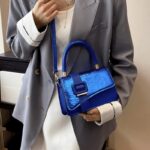 Femme élégante tenant le sac à main Gloria bleu, l'accessoire parfait pour compléter son look tendance.