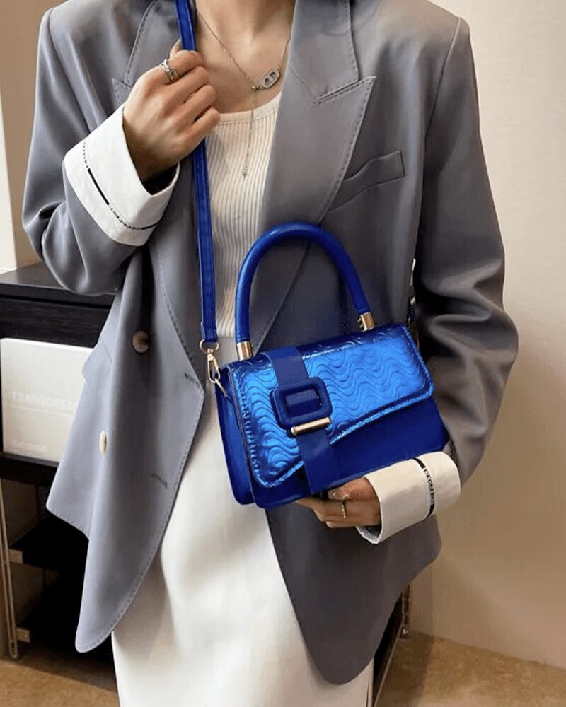 Femme élégante tenant le sac à main Gloria bleu, l'accessoire parfait pour compléter son look tendance.