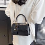 Femme chic arborant le sac à main Gloria noir, un accessoire intemporel pour une allure raffinée.