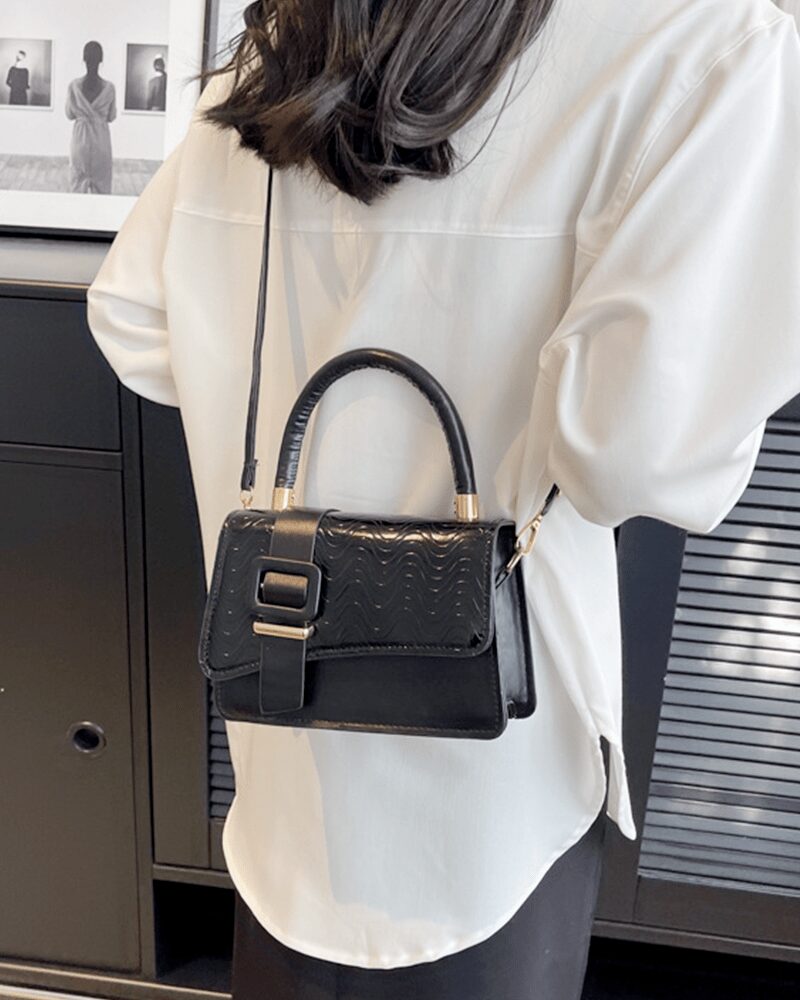 Femme chic arborant le sac à main Gloria noir, un accessoire intemporel pour une allure raffinée.