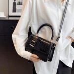 Femme élégante tenant fièrement le sac à main Gloria noir, un accessoire incontournable pour un style sophistiqué.