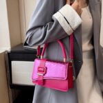 Femme raffinée arborant le sac à main Gloria rose, une touche de douceur pour un style distingué.