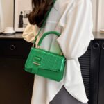 Femme chic arborant le sac à main Gloria vert, un accessoire raffiné pour un style distinctif.