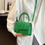 Femme tenant fièrement le sac à main Gloria vert, un accessoire chic pour un style vibrant.