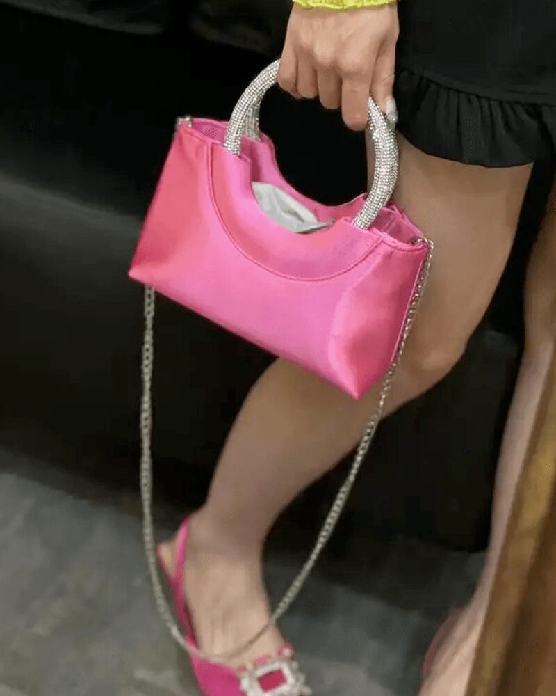 Myriam, l'accessoire incontournable : le sac à main en satin rose.