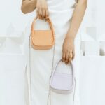 Affirmez votre sophistication avec le sac à main Shay, un accessoire chic tenu avec assurance à la main par les femmes de la boutique Izamel.