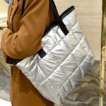 Découvrez la splendeur argentée du sac à main fourre-tout matelassé de Maïssane, un accessoire de choix porté avec assurance sur l'épaule par des femmes au style inégalé.