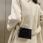 Femme élégante arborant le sac à main Megan noir craquelé en bandoulière, une déclaration de mode audacieuse.
