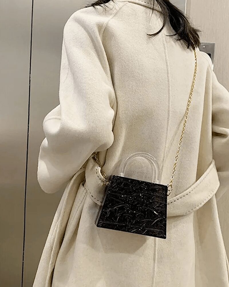 Femme élégante arborant le sac à main Megan noir craquelé en bandoulière, une déclaration de mode audacieuse.
