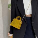 Femme au style dynamique avec le sac à main Megan orange craquelé en bandoulière, une déclaration audacieuse.