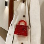 Femme arborant le sac à main Megan rouge craquelé en bandoulière, une touche de couleur vibrante pour un style audacieux.