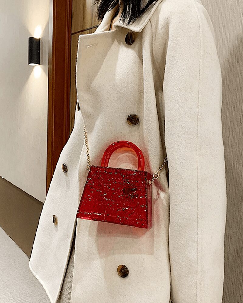 Femme arborant le sac à main Megan rouge craquelé en bandoulière, une touche de couleur vibrante pour un style audacieux.