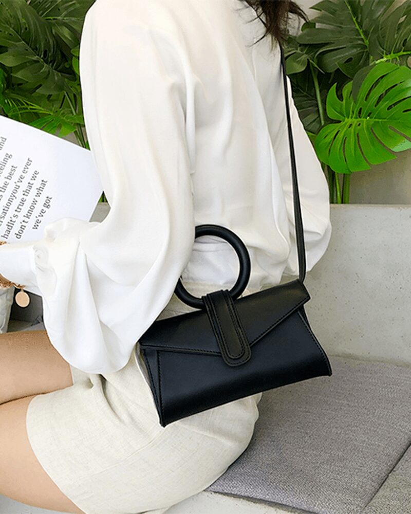Femme élégante portant le sac à main Jasmine en similicuir noir avec bandoulière - Accessoire de mode Izamel.