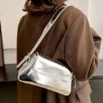 Affichez votre élégance avec le sac à main Molly en vernis argenté, conçu pour être porté à l'épaule, un choix parfait pour un look sophistiqué.