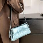 Affirmez votre style avec le sac à main Molly en vernis bleu, une pièce chic portée au bras, ajoutant une note de couleur vibrante à votre tenue.