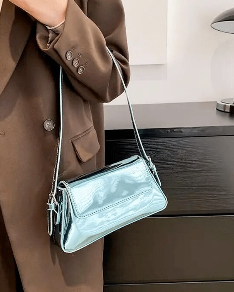 Affirmez votre style avec le sac à main Molly en vernis bleu, une pièce chic portée au bras, ajoutant une note de couleur vibrante à votre tenue.