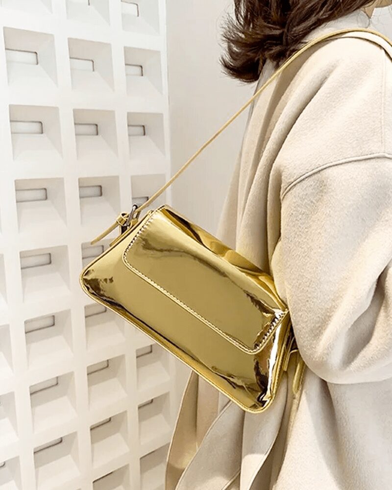 Illuminez votre style avec le sac à main Molly en vernis doré, une pièce luxueuse portée à l'épaule, pour une allure chic et glamour.
