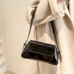 Sublimez votre style avec le sac à main Molly en vernis noir, conçu pour être porté gracieusement au bras, incarnant la sophistication et la praticité.