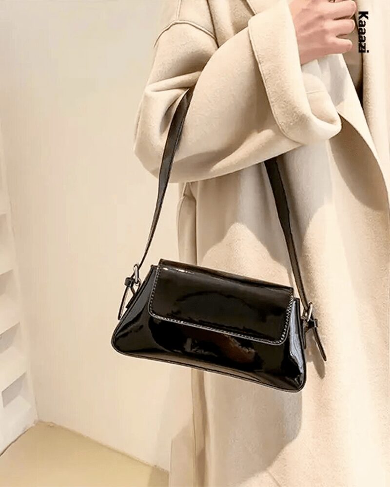 Sublimez votre style avec le sac à main Molly en vernis noir, conçu pour être porté gracieusement au bras, incarnant la sophistication et la praticité.