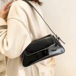 Le sac à main Molly en vernis noir, un accessoire emblématique pour les femmes qui préfèrent le port à l'épaule. Chic et polyvalent, il rehausse instantanément votre allure.