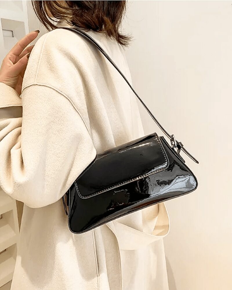 Le sac à main Molly en vernis noir, un accessoire emblématique pour les femmes qui préfèrent le port à l'épaule. Chic et polyvalent, il rehausse instantanément votre allure.