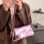 Faites ressortir votre côté féminin avec le sac à main Molly en vernis rose, une pièce délicate portée au bras, ajoutant une touche romantique à votre tenue.