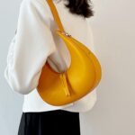 Sac à main en similicuir orange à Palma - Accessoire chic porté à l'épaule par des femmes.