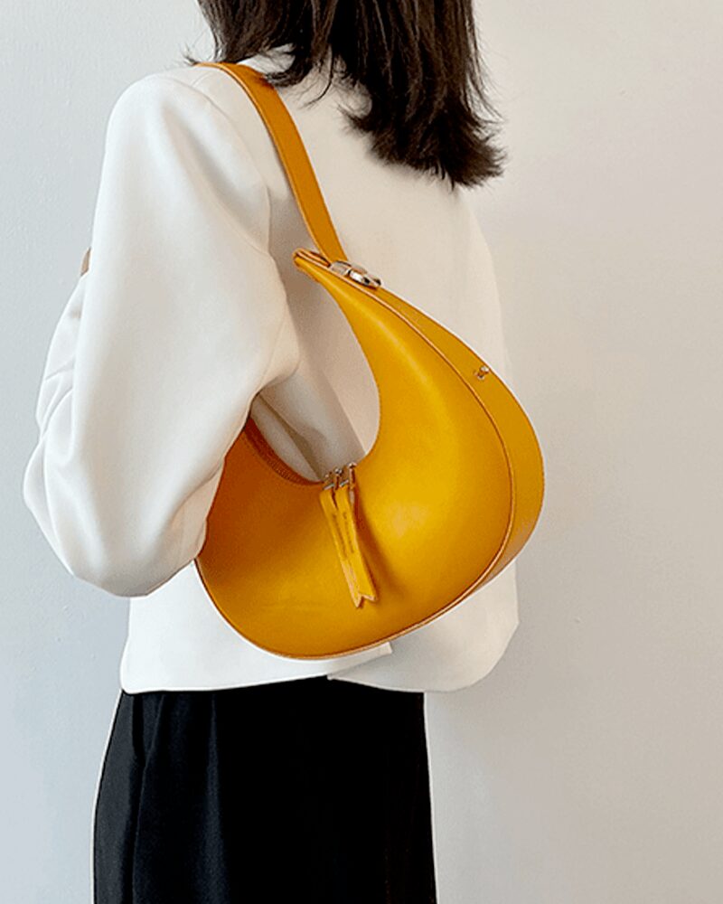 Sac à main en similicuir orange à Palma - Accessoire chic porté à l'épaule par des femmes.
