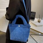 Découvrez le raffinement du Daisy Sac à Main Fourre-Tout en Velours Côtelé Bleu, une pièce incontournable portée avec élégance sur l'épaule, offrant un mélange parfait de style et de praticité.