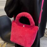 Le Daisy Sac à Main Fourre-Tout en Velours Côtelé Rose, un accessoire délicat qui incarne la féminité et le raffinement, parfaitement porté sur l'épaule.