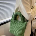 Élégance en Vert : Le Daisy Sac à Main Fourre-Tout en Velours Côtelé, une déclaration de style portée avec aisance en bandoulière par la femme moderne.