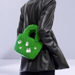 Sac à main Elisa en peluche vert avec strass - Accessoire de mode chic porté en bandoulière par une femme.