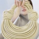 Sac à main Gaby tissé beige, tenu par une femme.