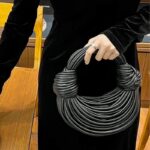 Sac à main Gaby tissé noir, tenu par une femme.