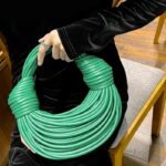 Sac à main Gaby tissé vert, porté par une femme.