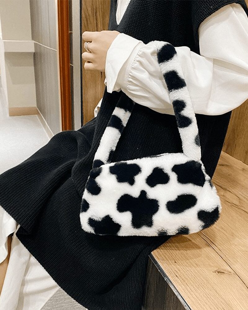 Sac à main motif vache Jamie en peluche, un accessoire élégant pour les femmes portant au bras.
