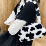 Sac à main motif vache Jamie en peluche, un accessoire tendance pour femmes portant à l'épaule.