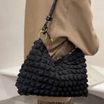 Découvrez le charme intemporel de Kate, le sac à main fourre-tout noir, magnifiquement porté sur l'épaule d'une femme, une déclaration de mode audacieuse.