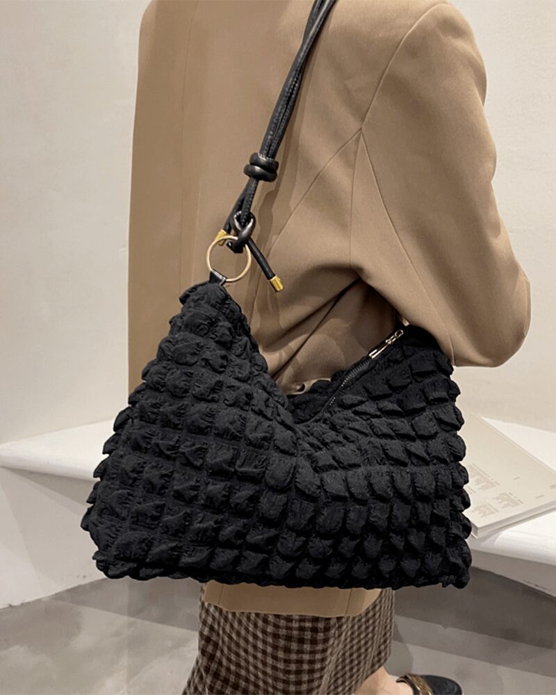 Découvrez le charme intemporel de Kate, le sac à main fourre-tout noir, magnifiquement porté sur l'épaule d'une femme, une déclaration de mode audacieuse.